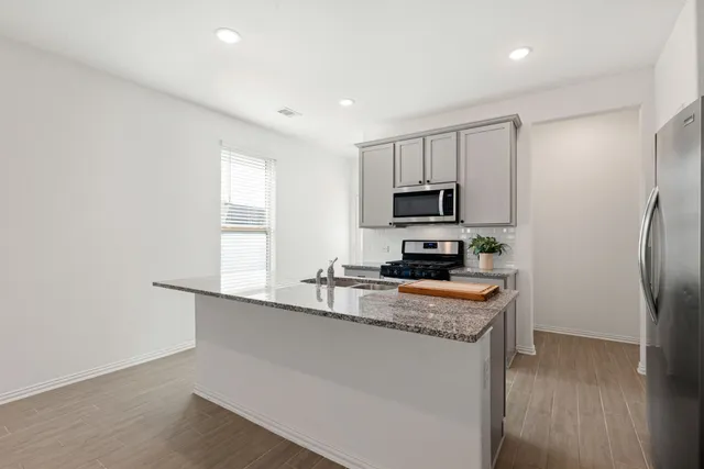 a kitchen with stainless steel appliances granite countertop a refrigerator a stove a sink and a microwave