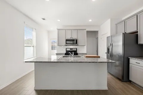 a kitchen with kitchen island granite countertop a sink appliances and cabinets
