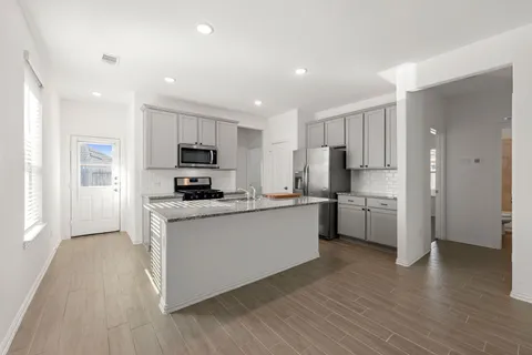 a kitchen with a refrigerator a stove top oven a sink and wooden floor