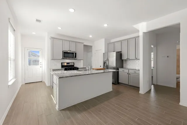 a kitchen with a refrigerator a stove top oven a sink and wooden floor