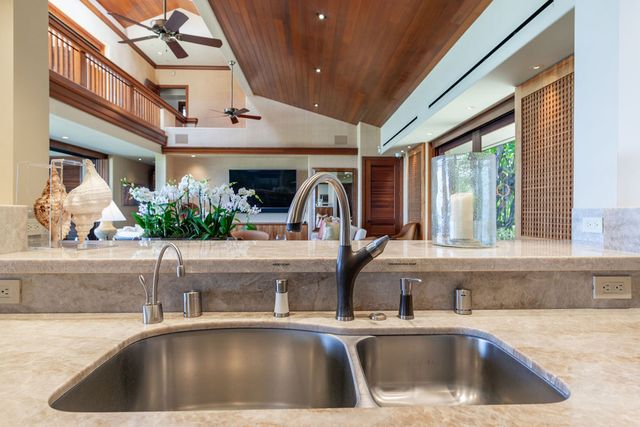 a kitchen sink with granite countertop a large window and sink