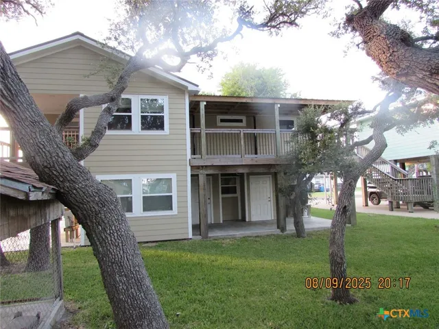 a view of a yard in front of a house with a large tree