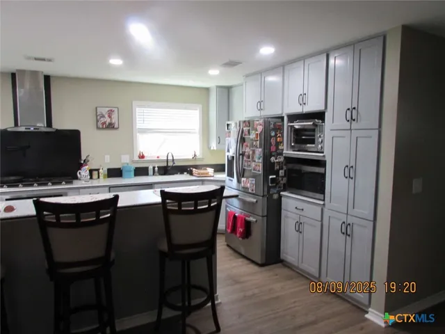 a kitchen with stainless steel appliances a refrigerator a stove a sink a dining table and chairs