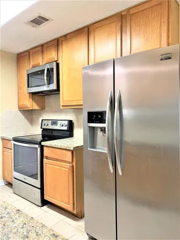 a kitchen with stainless steel appliances granite countertop a refrigerator a stove and a sink with wooden floor