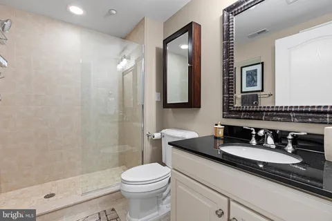 a bathroom with a granite countertop sink a toilet a mirror and shower