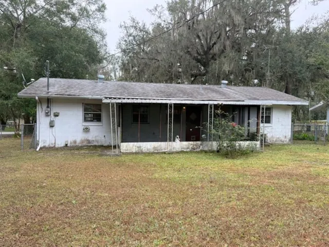 a backyard of a house with large trees and barbeque oven