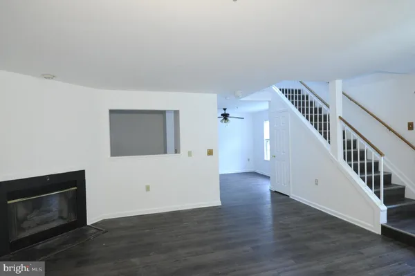 a view of an empty room with wooden floor and a fireplace