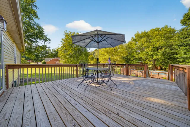 a view of a roof deck with table and chairs under an umbrella with wooden floor
