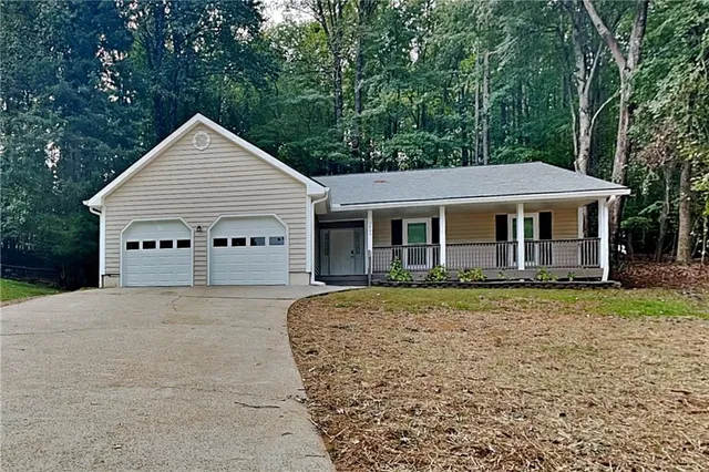 a view of a house with a yard plants and large tree