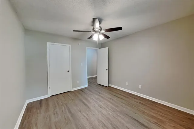 a view of an empty room with window a ceiling fan and wooden floor