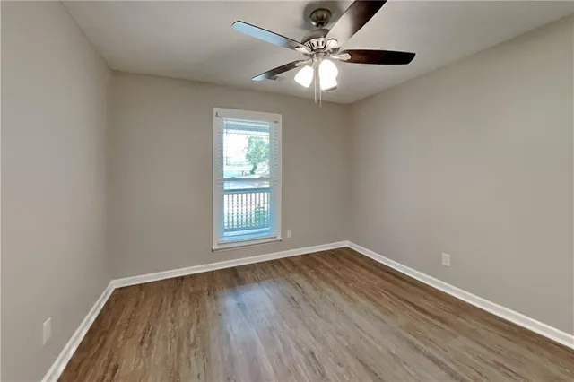 an empty room with wooden floor chandelier fan and window