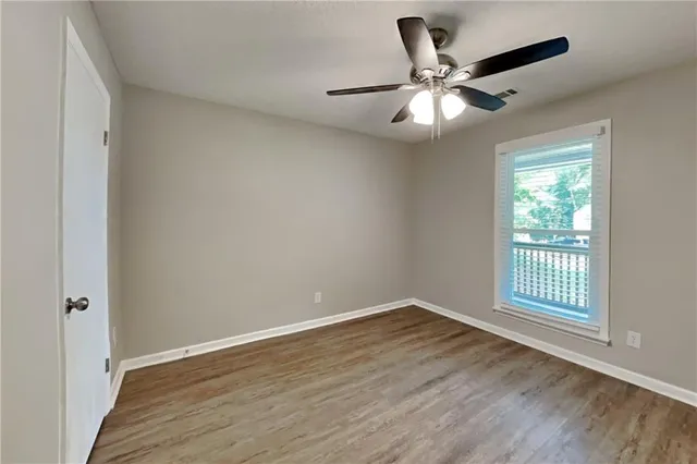 a view of an empty room with wooden floor and a window
