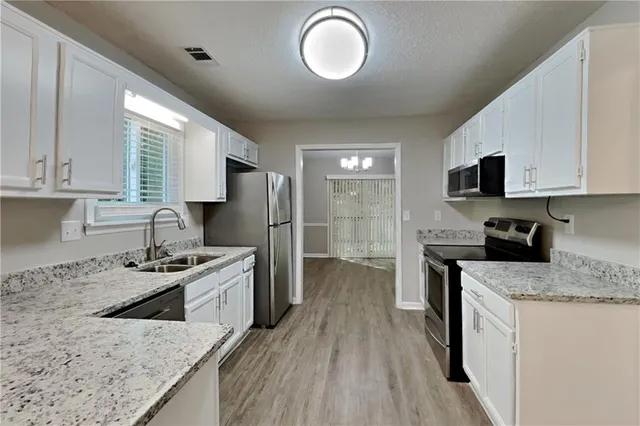 a kitchen with stainless steel appliances granite countertop a sink stove refrigerator and cabinets