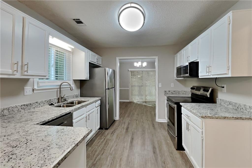 3883 Nowlin Road Kennesaw, GA 30144 - Photo 5 of 21 a kitchen with stainless steel appliances granite countertop a sink stove refrigerator and cabinets