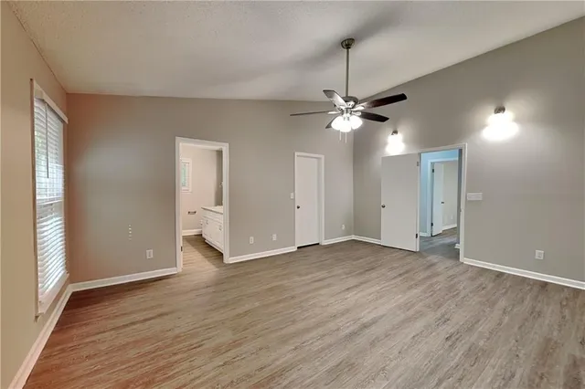 an empty room with wooden floor fan and windows
