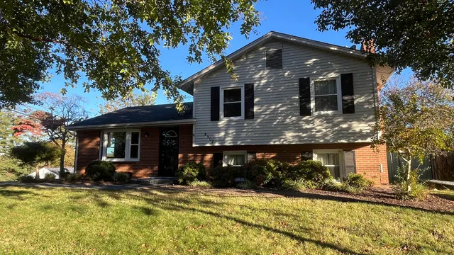 a front view of a house with a yard outdoor seating and covered with trees