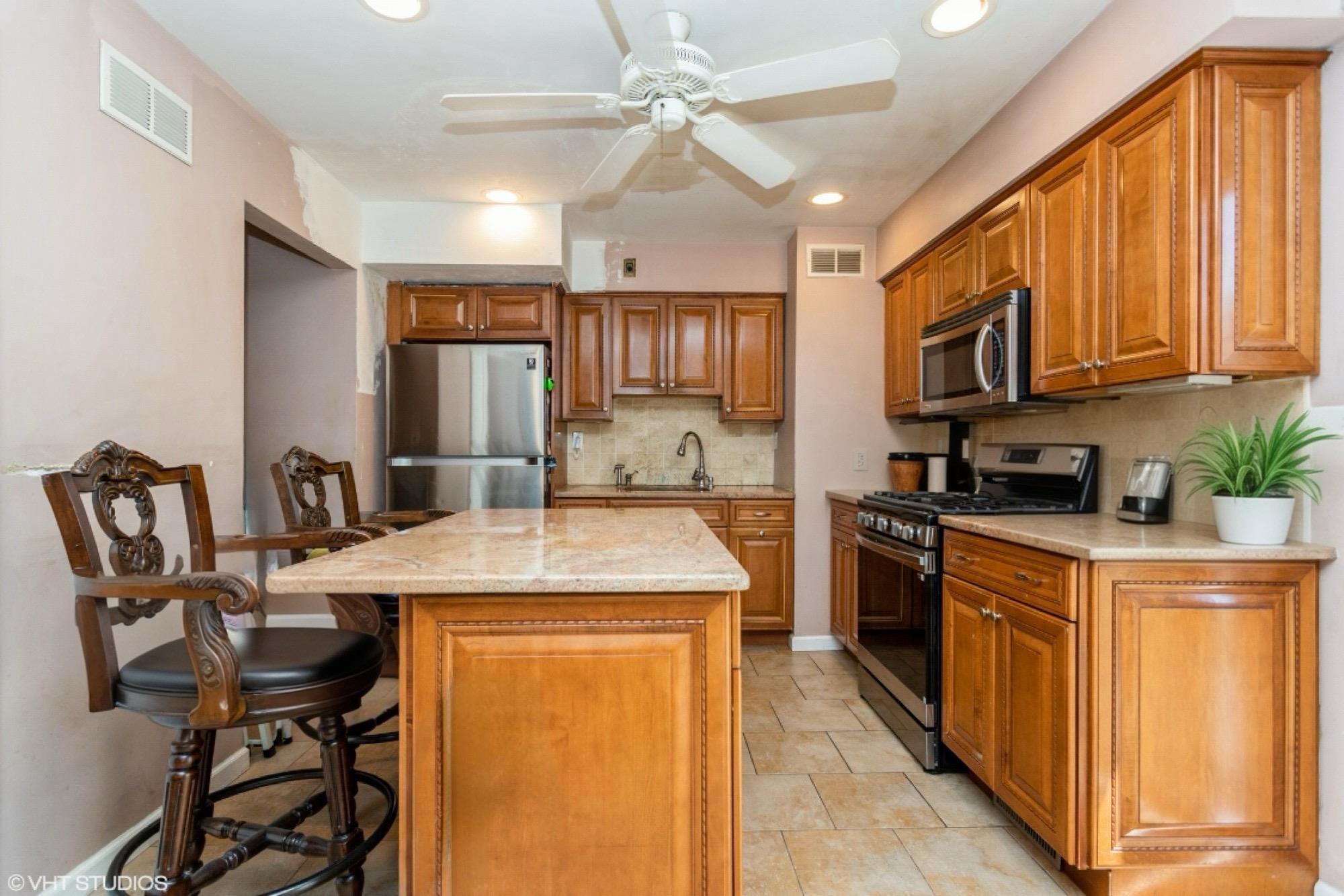 15 Sharon Drive Spring Valley, NY 10977 - Photo 5 of 24 Kitchen with stainless steel appliances, tasteful backsplash, brown cabinetry, ceiling fan, and a center island