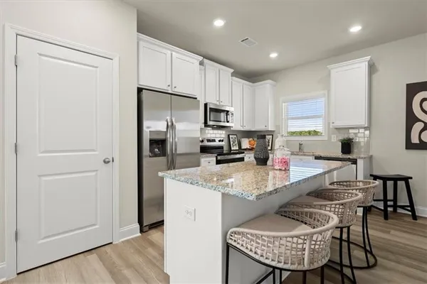 a kitchen with stainless steel appliances granite countertop a stove a refrigerator a sink a dining table and chairs