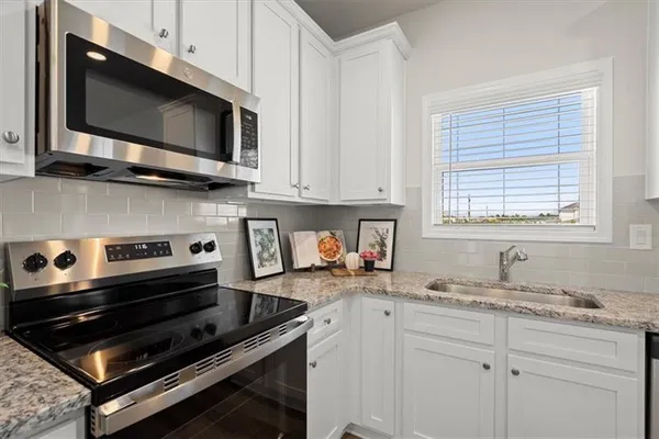 a kitchen with granite countertop a stove microwave and sink