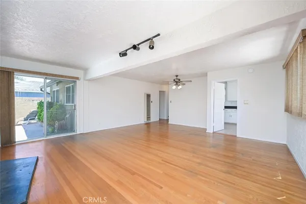 a view of an empty room with window and wooden floor