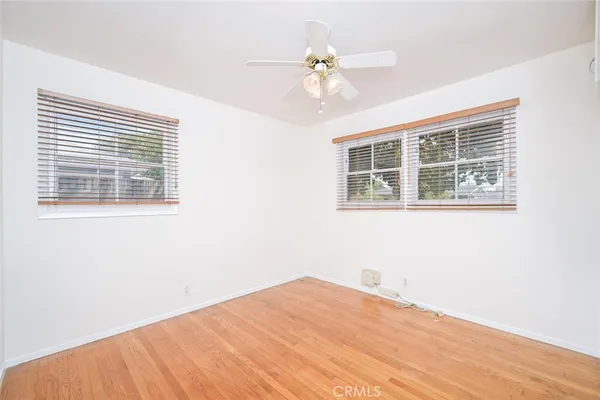 a view of empty room with wooden floor and ceiling fan