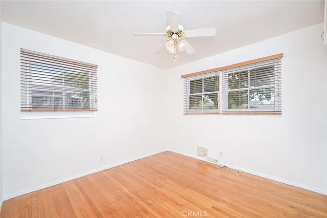 a view of empty room with wooden floor and ceiling fan