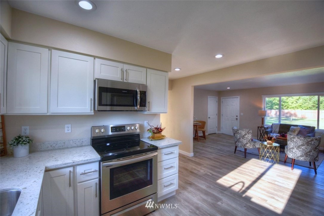 8231 James Road Southwest Rochester, WA 98579 - Photo 6 of 25 a kitchen with stainless steel appliances a stove a sink cabinets and a wooden floor