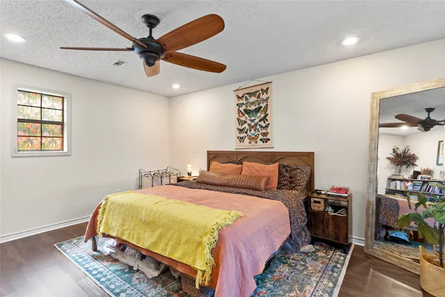 a bedroom with a bed a dresser and wooden floor