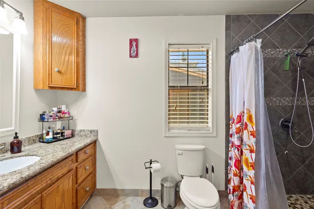 a bathroom with a granite countertop sink and a toilet