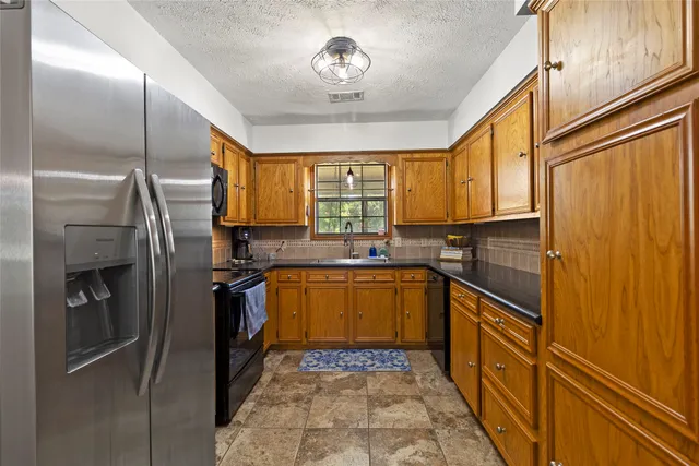 a kitchen with stainless steel appliances granite countertop a refrigerator and a sink