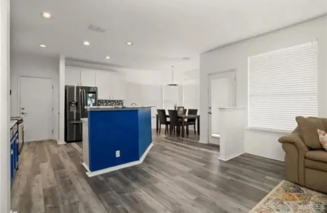 a kitchen with stainless steel appliances kitchen island granite countertop a refrigerator oven a sink with island and chairs