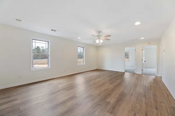 a view of an empty room with wooden floor and window