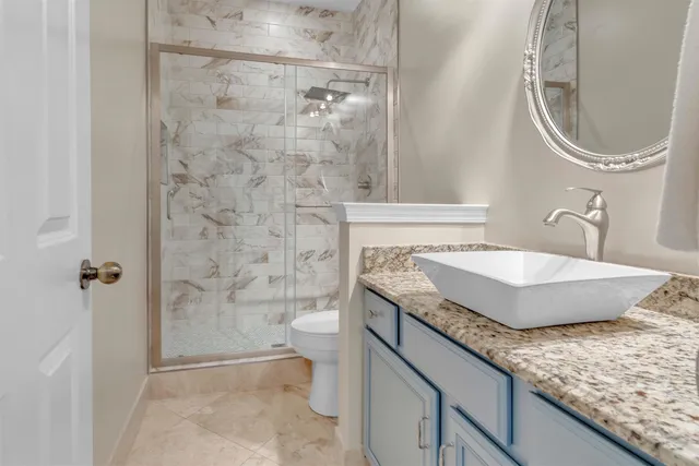 a bathroom with a granite countertop sink a toilet and shower