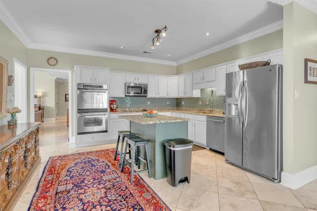 a kitchen with stainless steel appliances granite countertop a refrigerator a stove top oven and sink with wooden floor