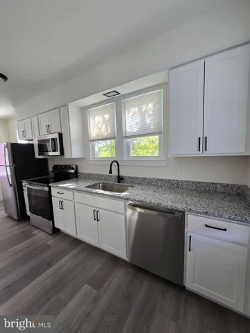 a kitchen with granite countertop cabinets stainless steel appliances a sink and a window