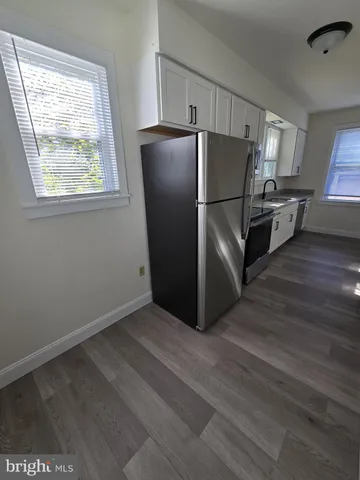 a view of kitchen with stainless steel appliances wooden floor and window