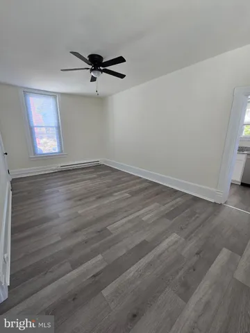 an empty room with wooden floor a ceiling fan and windows