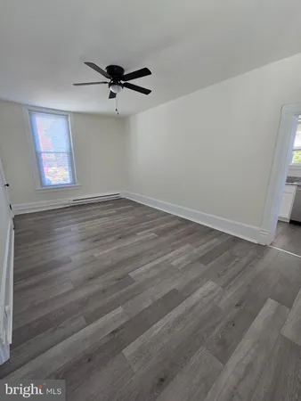 an empty room with wooden floor a ceiling fan and windows