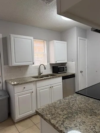 a kitchen with granite countertop sink stove and cabinets