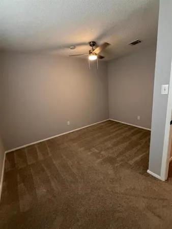 an empty room with a ceiling fan and carpet