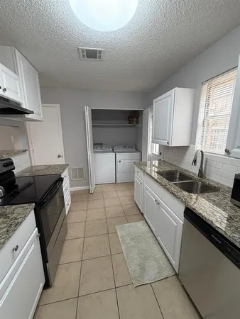 a large kitchen with a stove a sink dishwasher and cabinets