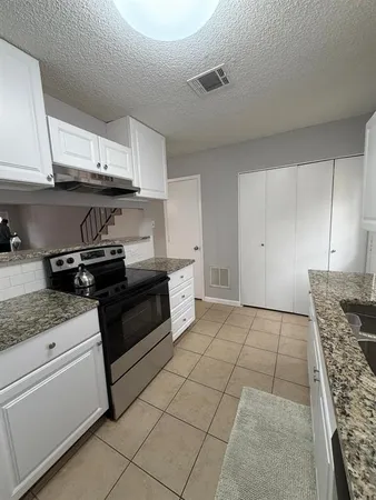 a kitchen with granite countertop a stove a sink and a microwave