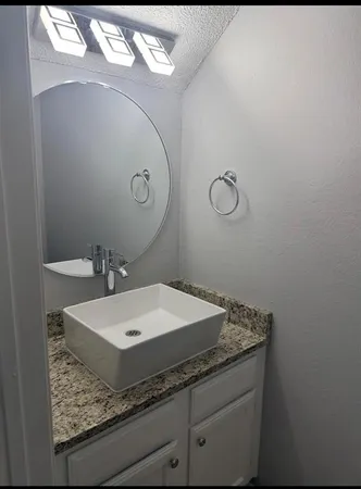 a bathroom with a granite countertop sink and a mirror