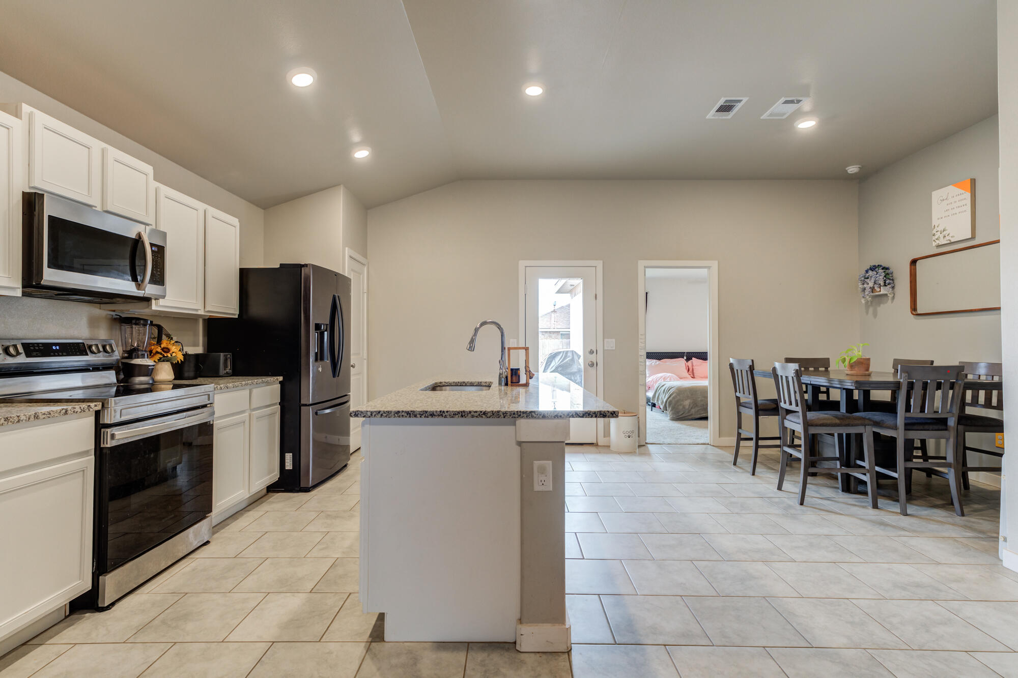 7429 31st Street Lubbock, TX 79407 - Photo 9 of 29 a kitchen with stainless steel appliances granite countertop a stove top oven a sink a dining table and chairs