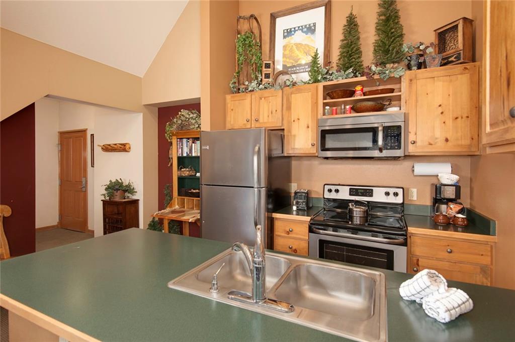129 River Run Road, Unit 8071 Keystone, CO 80435 - Photo 4 of 21 a kitchen with stainless steel appliances granite countertop a refrigerator a stove and a sink with wooden floor