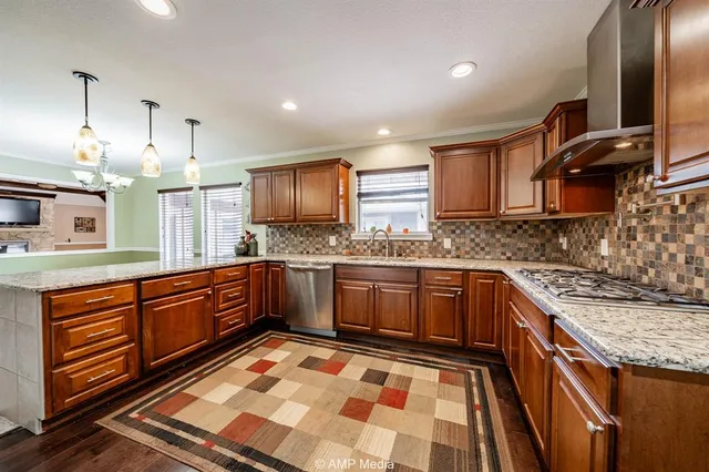 a kitchen with stainless steel appliances granite countertop a sink and wooden cabinets