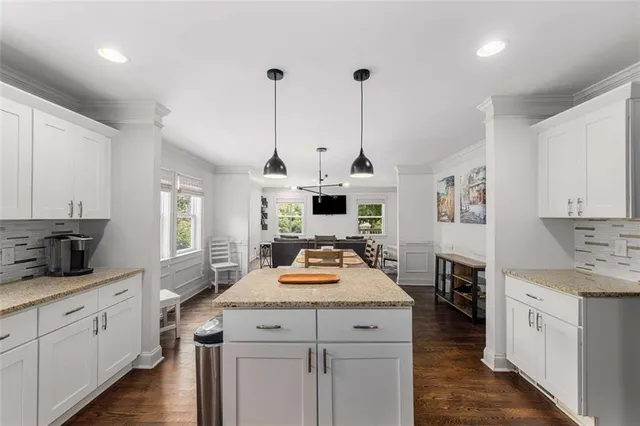 a kitchen with a stove a sink a kitchen island with wooden cabinets and wooden floor