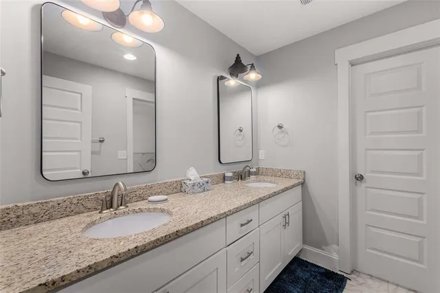 a bathroom with a granite countertop double vanity sink and mirror