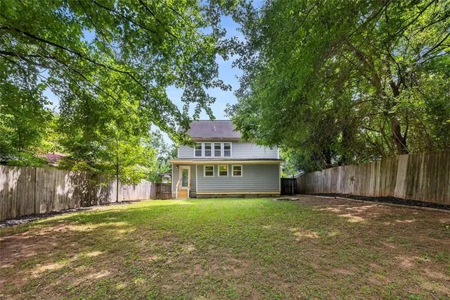 a view of a house with a big yard and large tree