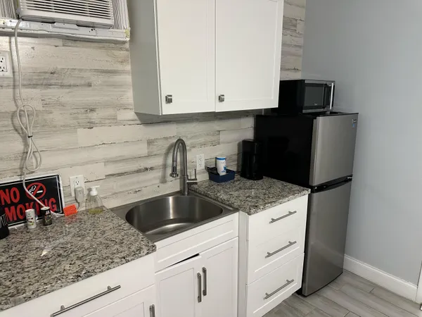 a kitchen with granite countertop white cabinets sink and stainless steel appliances
